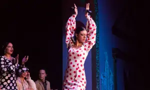 Bailarina de flamenco andaluz con vestido de lunares rojos, castañuelas en alto.
