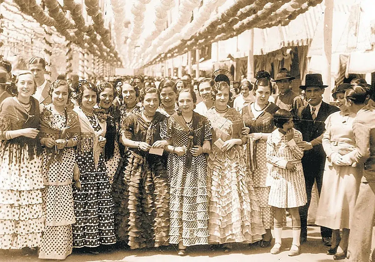 Un grupo de mujeres y ni&ntilde;as con trajes de flamenca, un reflejo del origen del traje de flamenca en una feria antigua.