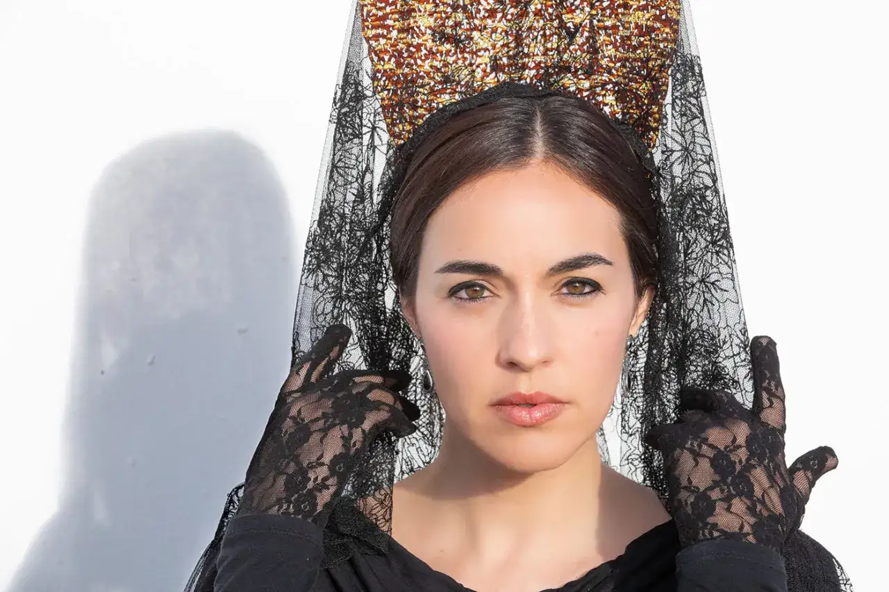 Mujer con mantilla negra y guantes de encaje, lista para aprender como hacer mo&ntilde;o para mantilla.