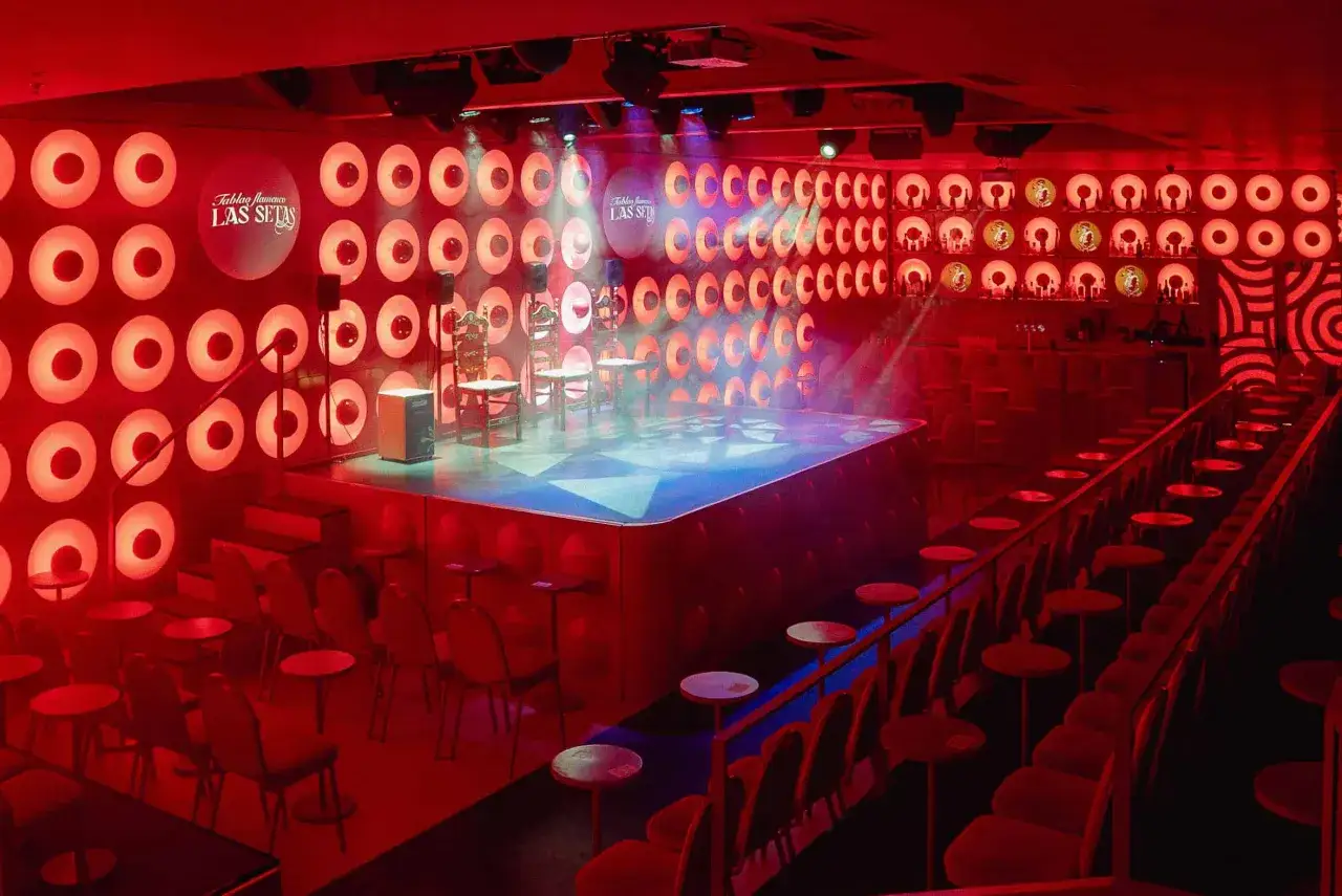 Escenario listo para un espect&aacute;culo de flamenco catal&aacute;n en el Tablao Las Setas, con sillas, un caj&oacute;n y luces rojas.