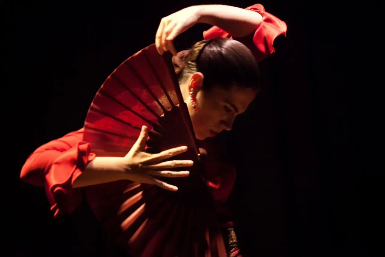 Bailarina de flamenco con abanico rojo, su movimiento evoca la pasi&oacute;n y el arte de la guajira.