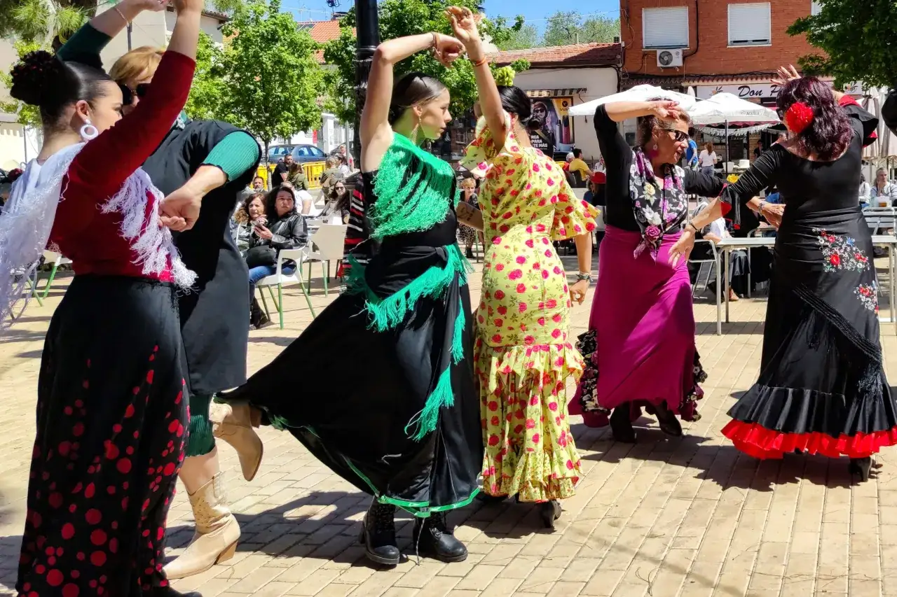 Grupos de sevillanas bailan con pasi&oacute;n bajo el sol, sus faldas ondean al ritmo de la m&uacute;sica.