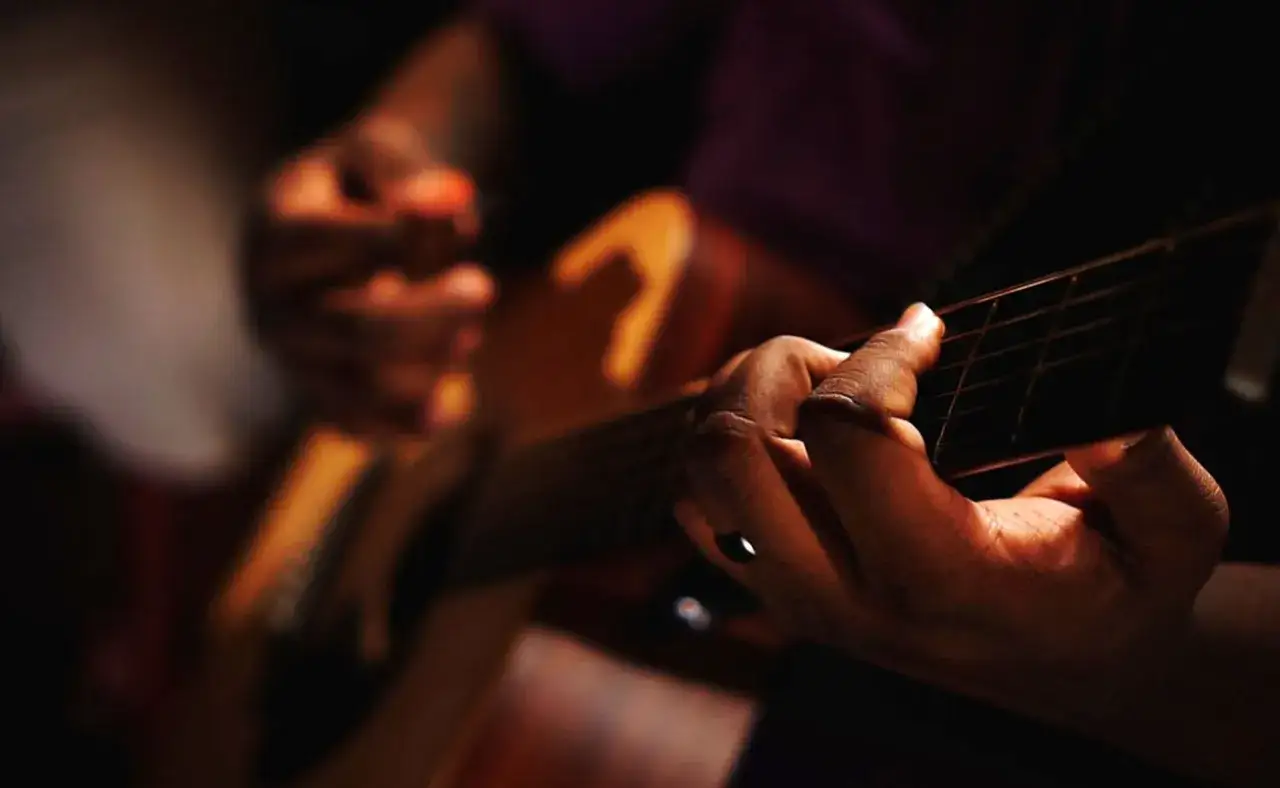 Manos tocando guitarra, creando un soniquete que es pura emoci&oacute;n.