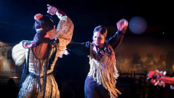 Dos mujeres bailan flamenco, el baile típico de España, con pasión y gracia. Sus trajes vibrantes y movimientos expresivos capturan la esencia de esta arte.